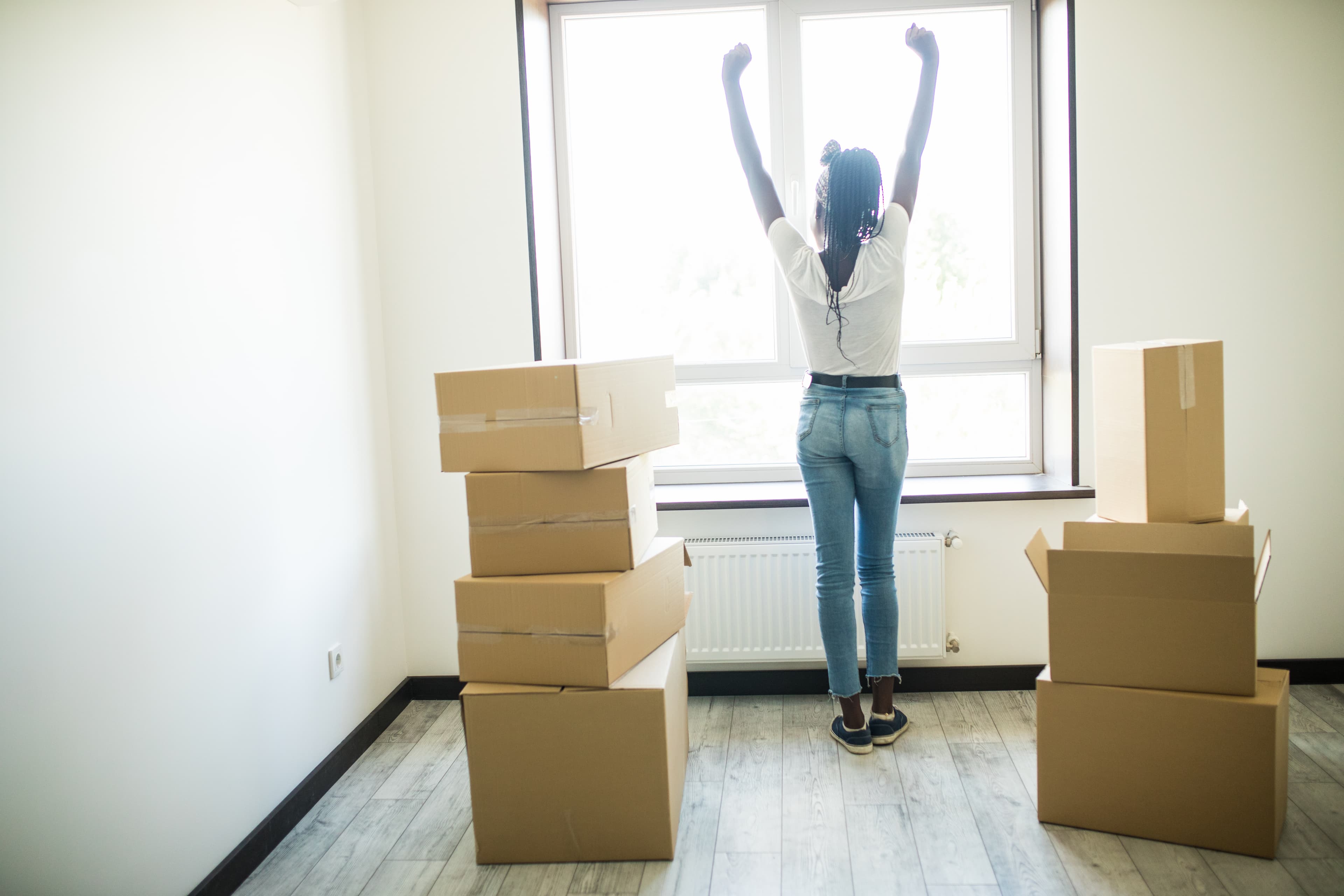 A renter celebrating with arms raised in her new, sunlit home